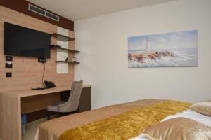 a bedroom with a bed and a desk with a television at Hotel Meduza in Senj