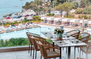 a restaurant with a table and chairs and a pool at Vincci EverEden in Anavyssos