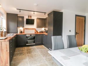 a kitchen with black cabinets and a table with a bowl of fruit at 6 Lock View in Skipton