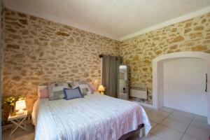 a bedroom with a bed and a stone wall at Portail Du Ventoux Central Luxe Jardin Linge fourni in Malaucène