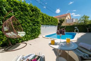 un patio con una mesa junto a la piscina en Apartments Orlic en Trogir