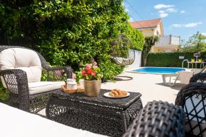 een patio met rieten stoelen en een tafel met eten erop bij Apartments Orlic in Trogir