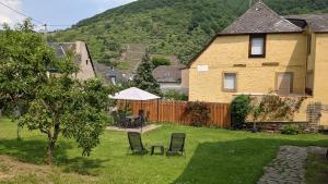 einen Hof mit zwei Stühlen, einem Tisch und einem Haus in der Unterkunft Ferienwohnung Ewa in Ellenz-Poltersdorf