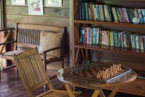um tabuleiro de xadrez numa mesa de vidro ao lado de uma estante de livros em Pousada Mangabeiras na Ilha de Boipeba