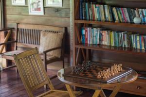 a chess board on a glass table next to a book shelf at Pousada Mangabeiras in Ilha de Boipeba