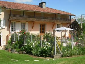 un jardin avec un parasol en face d'une maison dans l'établissement Le Clos Fleuri, à Caumont
