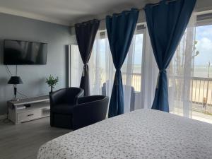 een slaapkamer met een bed, een stoel en een raam bij Le Cheval Bleu in La Baule