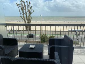 a balcony with chairs and a table and a beach at Le Cheval Bleu in La Baule