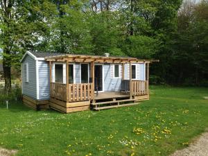 mały domek z tarasem w trawie w obiekcie Jelling Family Camping & Cottages w mieście Jelling