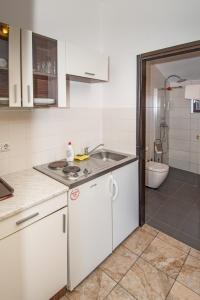 a white kitchen with a sink and a bathroom at Breakfast & Bed Anita in Medulin