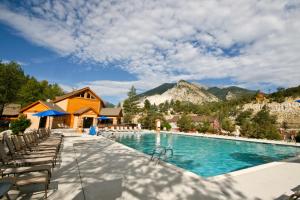 a swimming pool with chairs and mountains in the background at Mount Princeton Hot Springs Resort in Buena Vista