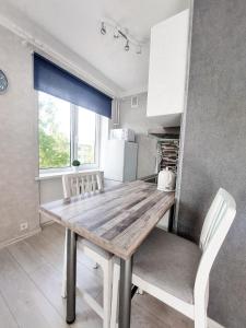 a kitchen with a wooden table and white chairs at Centrum Apartement in Valga