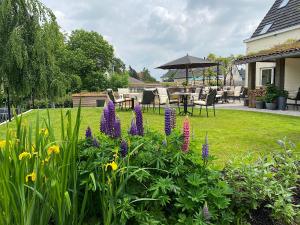 un jardín con flores púrpuras, mesa y sillas en Horenbecca Bistro & Wellness, en Horebeke