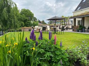 HorebekeにあるHorenbecca Bistro & Wellnessの紫の花が咲く庭園(テーブル、椅子付)