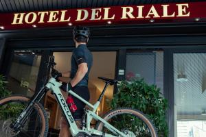 un hombre sosteniendo una bicicleta en frente de un hotel delride en Hotel Del Riale, en Parabiago