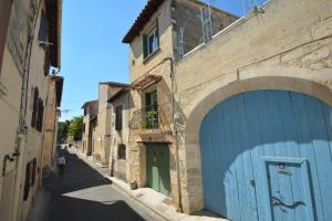 Une allée dans une vieille ville avec un garage bleu dans l'établissement Maison Le Petit Balcon Beaucaire, à Beaucaire