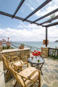 eine Terrasse mit einem Tisch, Stühlen und Meerblick in der Unterkunft Coral Front Beach in Káto Zákros