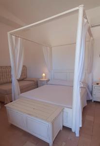 a bedroom with a white canopy bed and a couch at Antica Masseria Ficazzana - Tenuta in Marina di Pescoluse