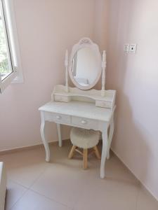 a white dressing table with a mirror and a stool at Sozia in Perdika