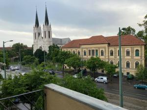 a large building with a church and a street with cars at Daylight City Center in Szeged