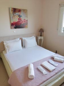 Un dormitorio con una cama blanca con toallas. en Sozia, en Perdika