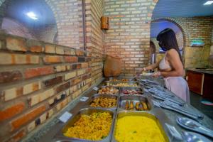 a woman standing in front of a buffet of food at Coliseum Beach Resort All Inclusive in Beberibe