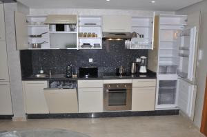 une cuisine avec des armoires blanches et un comptoir noir dans l'établissement Luxueux appartement pied dans l'eau sur la plage d'Imi Ouaddar, à Agadir nʼ Aït Sa