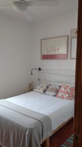 una camera da letto con un letto con lenzuola bianche e una foto sul muro di 4 Vents Cala Galdana a Cala Galdana