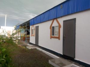 a white building with a blue roof and a door at Отдых в Капшагае! in Kapchagay