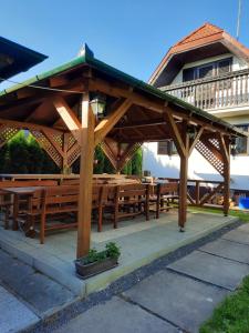 a wooden pavilion with wooden tables and benches at Vadása Nyaralóház in Őrimagyarósd