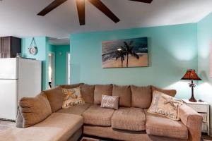 a living room with a brown couch and a refrigerator at Turtles Nest in Dauphin Island