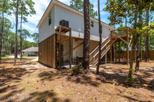 a house in the woods with a deck and stairs at Turtles Nest in Dauphin Island