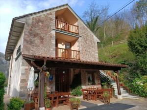 a house with a balcony and wooden tables and benches at La Salmonera Cangas de Onís in Caño