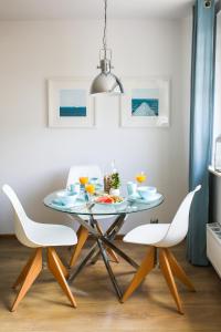 Apartament Błękitno na Białym في فواديسوافوفو: طاولة طعام مع كرسيين بيض وطاولة زجاجية