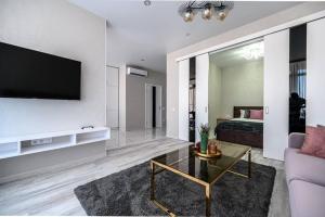a living room with a couch and a tv on a wall at Комфортные апартаменты 36 жемчужина in Odesa