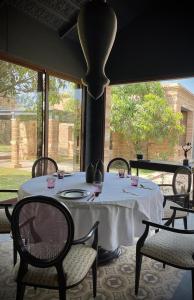 uma mesa com uma toalha de mesa branca, cadeiras e janelas em The Postcard Gir Wildlife Sanctuary em Sasan Gir