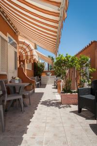 un patio con tavoli, sedie e ombrellone in legno di B&B La Pineta a Orbetello