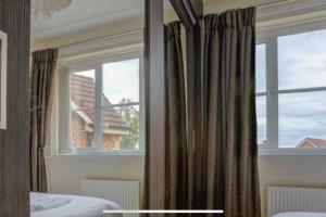Luxury 4 Bedroom House في مانشستر: غرفة نوم بسرير ونافذة مع ستائر