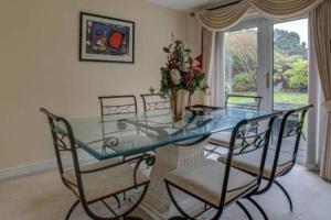 a glass table with four chairs and a vase with flowers at Luxury 4 Bedroom House in Manchester