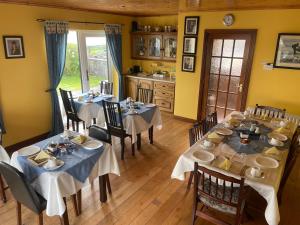 una sala da pranzo con tavoli e sedie e una cucina di Cois Farraige a Lahinch