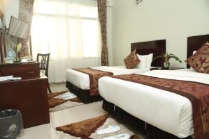 a hotel room with two beds and a desk at Adden Palace Hotel & Conference Centre in Mwanza