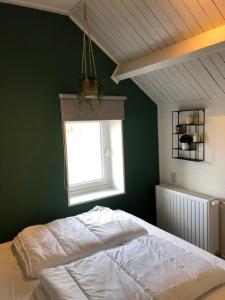 a bedroom with a white bed and a window at Huisje op den Diek in Sint Kruis