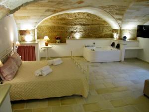 una camera da letto con vasca e un letto con asciugamani di La Vecchia Grotta a Maruggio