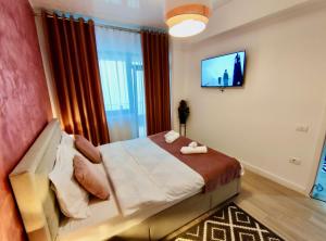 ein Schlafzimmer mit einem Bett und einem Fernseher an der Wand in der Unterkunft Primera Residence Mamaia Nord in Mamaia Nord – Năvodari