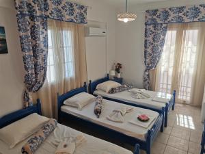 2 Betten in einem Zimmer mit blauen und weißen Vorhängen in der Unterkunft Aiantas in Ermoupoli