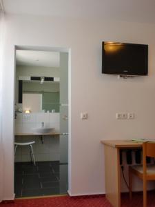 Habitación con escritorio y TV en la pared. en Hotel & Gästehaus Krone, en Geiselwind