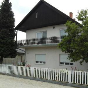 une maison blanche avec un toit noir et une clôture blanche dans l'établissement Pipacs apartmanok, à Balatonboglár