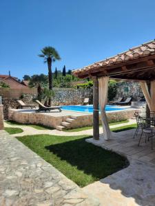 a backyard with a swimming pool and a pavilion at Villa Guardian in Čilipi