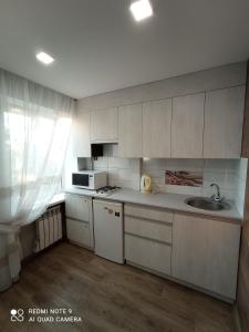 ドニプロにあるlark apartmentの白いキャビネットとシンク付きのキッチン