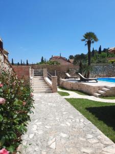 a stone walkway next to a pool with a palm tree at Villa Guardian in Čilipi